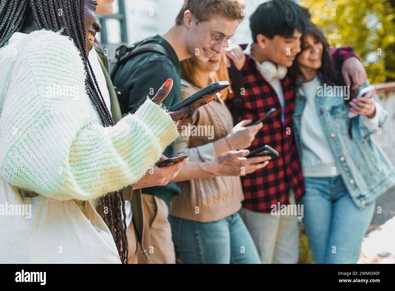 Gruppe von Freunden, die Smartphones nutzen – Interaktion in sozialen Medien – Konnektivität, Teilen, Jugend, Freizeit im Freien. Stockfoto