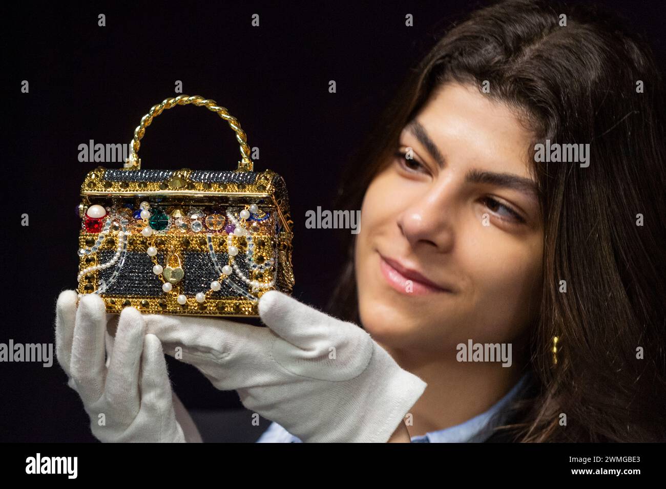 London, Großbritannien. 26. Februar 2024. Ein Mitarbeiter mit einer Judith Leiber: Gold „Sunken Treasure Chest“ Clutch Bag, 2022, (Est. £600 - £800) bei einer Vorschau auf Bonhams bevorstehende Designer Handtaschen und Fashion Sale. Luxuriöse Handtaschen und Ready-to-Wear-Designs werden am 28. Februar in den Bonhams Knightsbridge Galeries versteigert. Quelle: Stephen Chung / Alamy Live News Stockfoto