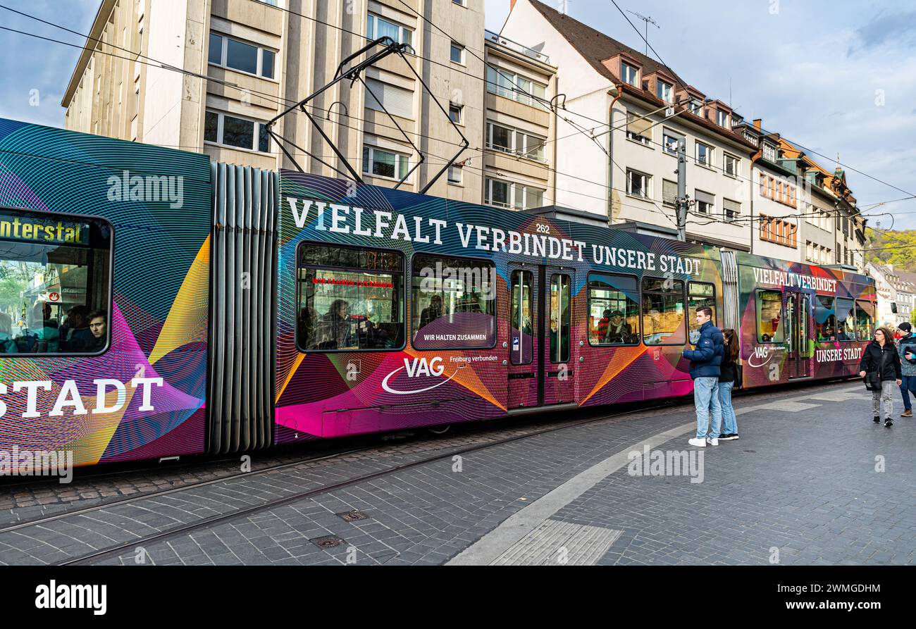 Eine Strassenbahn mit der seitlichen Aufschrift 'Vielfalt verbindet unsere Stadt' fährt beim Platz der alten Synagoge vorbei. (Freiburg im Breisgau, D Stockfoto