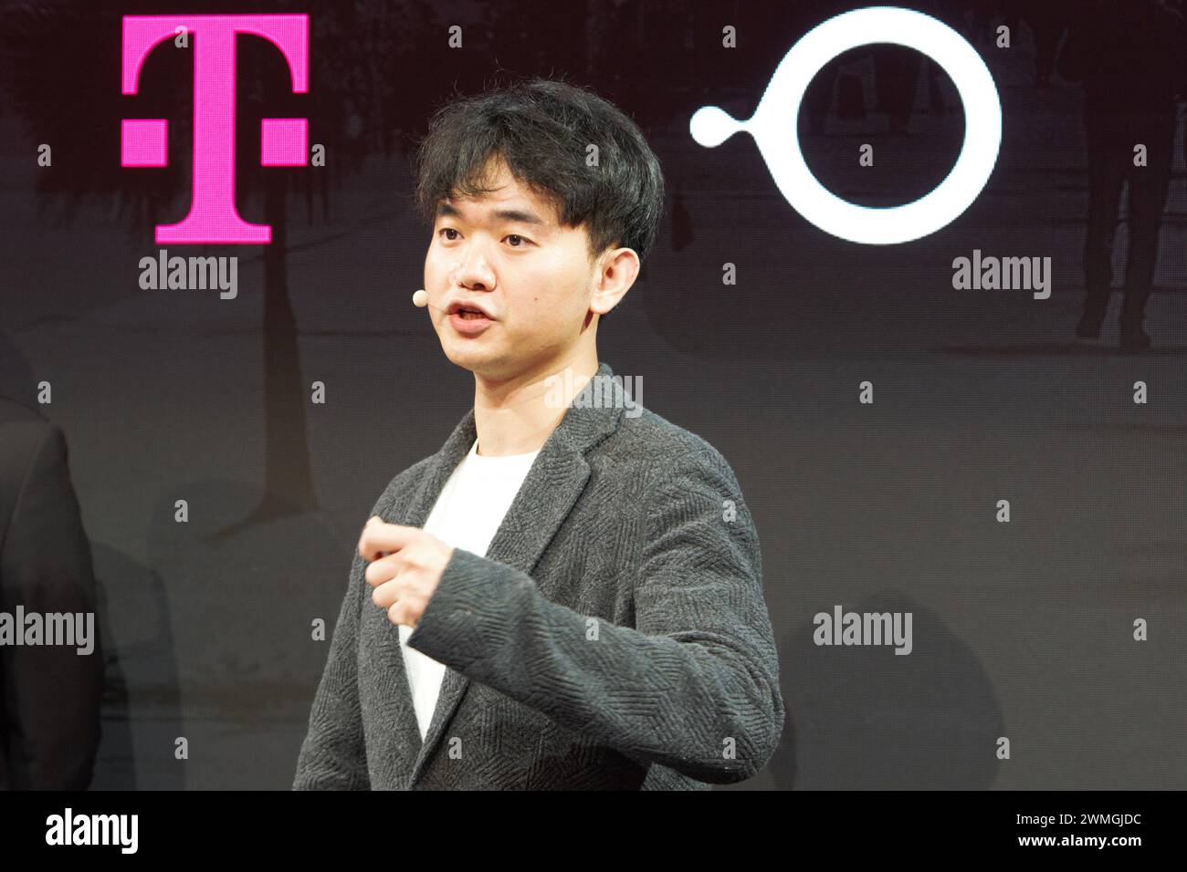 Barcelona, Spanien. Februar 2024. Jerry Yue, Gründer und CEO des US-amerikanischen Technologieunternehmens Brain Technologies, steht auf der Bühne des Mobile World Congress (MWC) und stellt einen Prototyp eines Smartphones der Deutschen Telekom vor. Sie verwenden keine Apps mehr auf Ihrem Smartphone, sondern geben stattdessen die KI-Sprachbefehle, woraufhin die KI das Internet durchsucht und Vorschläge auf dem Smartphone-Bildschirm anzeigt. Quelle: Wolf von Dewitz/dpa/Alamy Live News Stockfoto