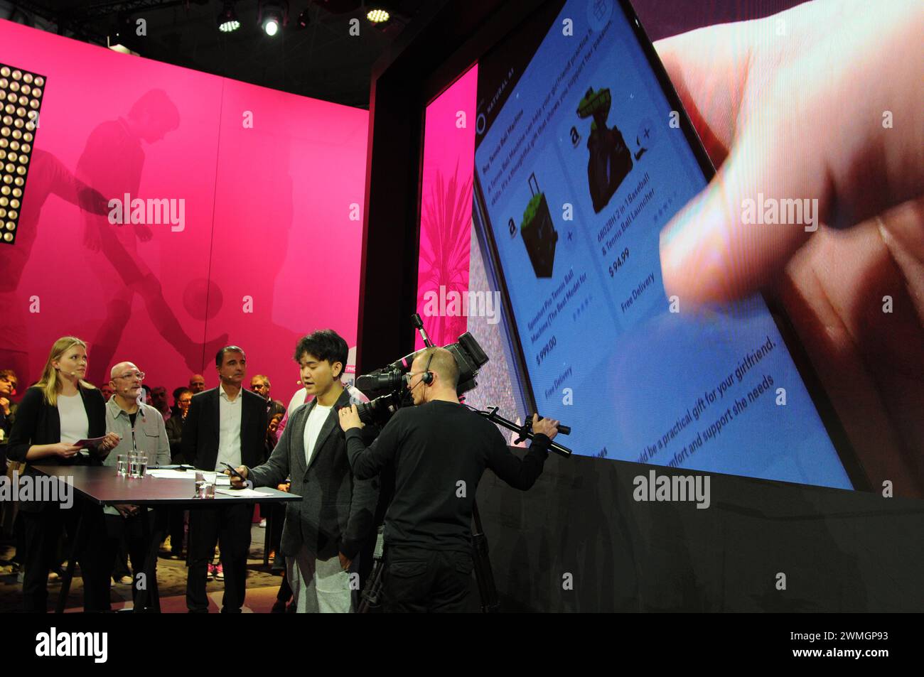 Barcelona, Spanien. Februar 2024. Jerry Yue, Gründer und CEO des US-amerikanischen Technologieunternehmens Brain Technologies, steht auf der Bühne des Mobile World Congress (MWC) und stellt einen Prototyp eines Smartphones der Deutschen Telekom vor. Auf dem Bildschirm hinter ihm sehen Sie Geschenkvorschläge, die ihm von einer künstlichen Intelligenz gemacht wurden. Er kommuniziert mit der KI per Sprachbefehl und benötigt keine Apps mehr. Neben ihm sind Vertreter der Deutschen Telekom und des Chipherstellers Qualcomm. Quelle: Wolf von Dewitz/dpa/Alamy Live News Stockfoto