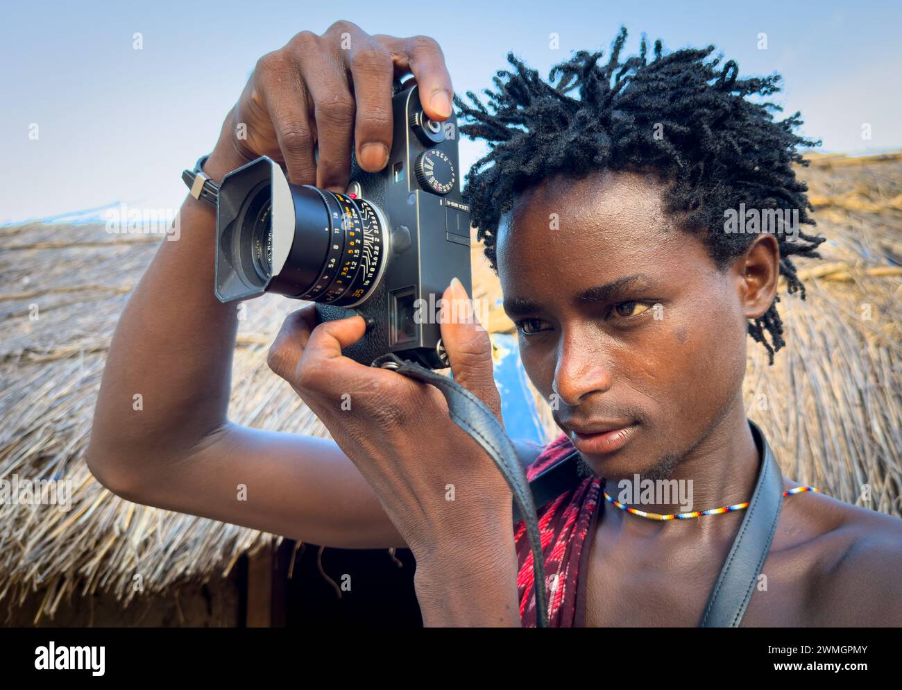 Ein junger Maasai-Krieger nutzt eine Leica M10-R Digitalkamera in seinem Dorf in Mikumi, Tansania. Stockfoto