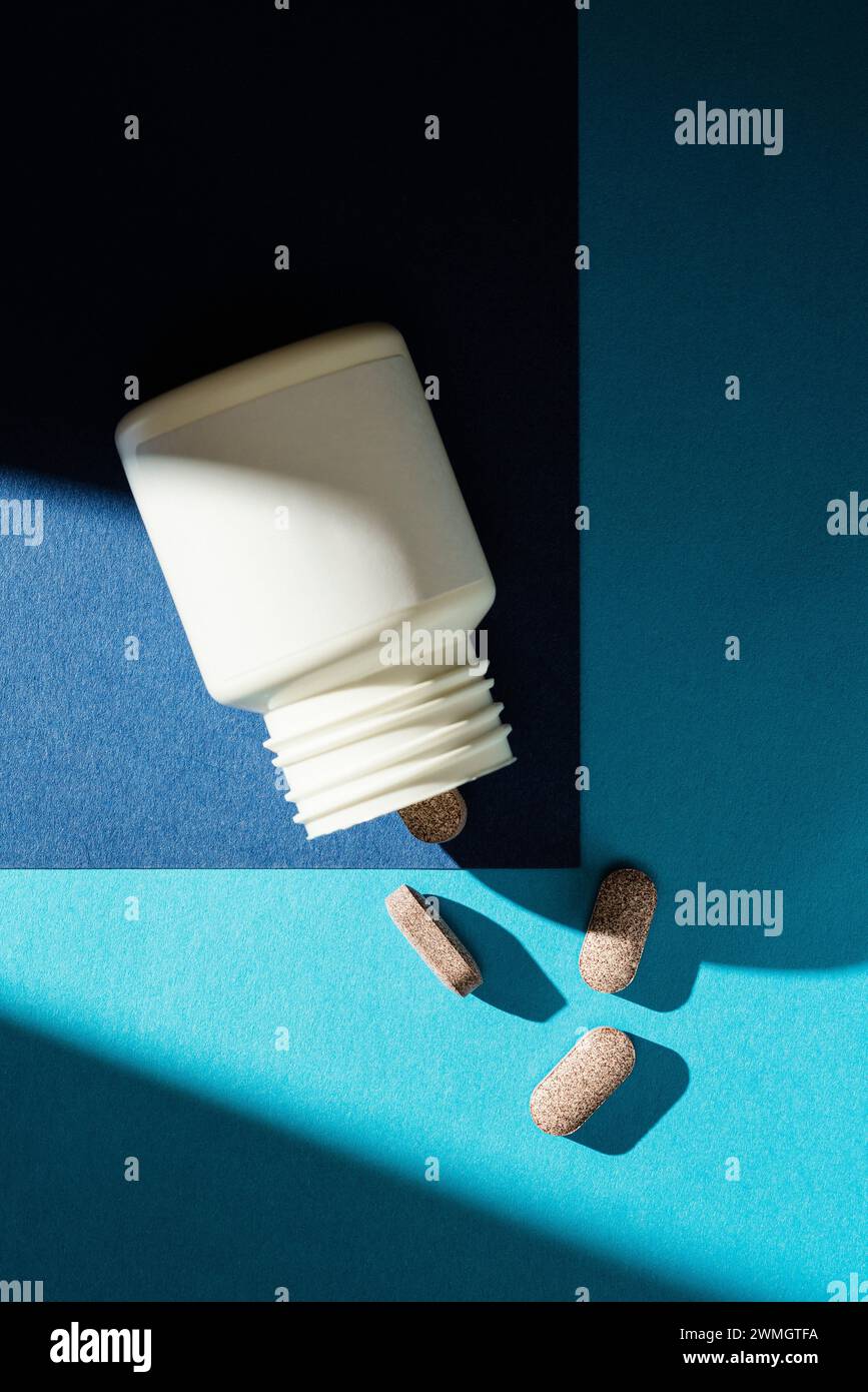 Tablettenpillen aus dem Modell der weißen Pille Flasche mit leerem Kopierraum auf blauem Hintergrund verschüttet Stockfoto