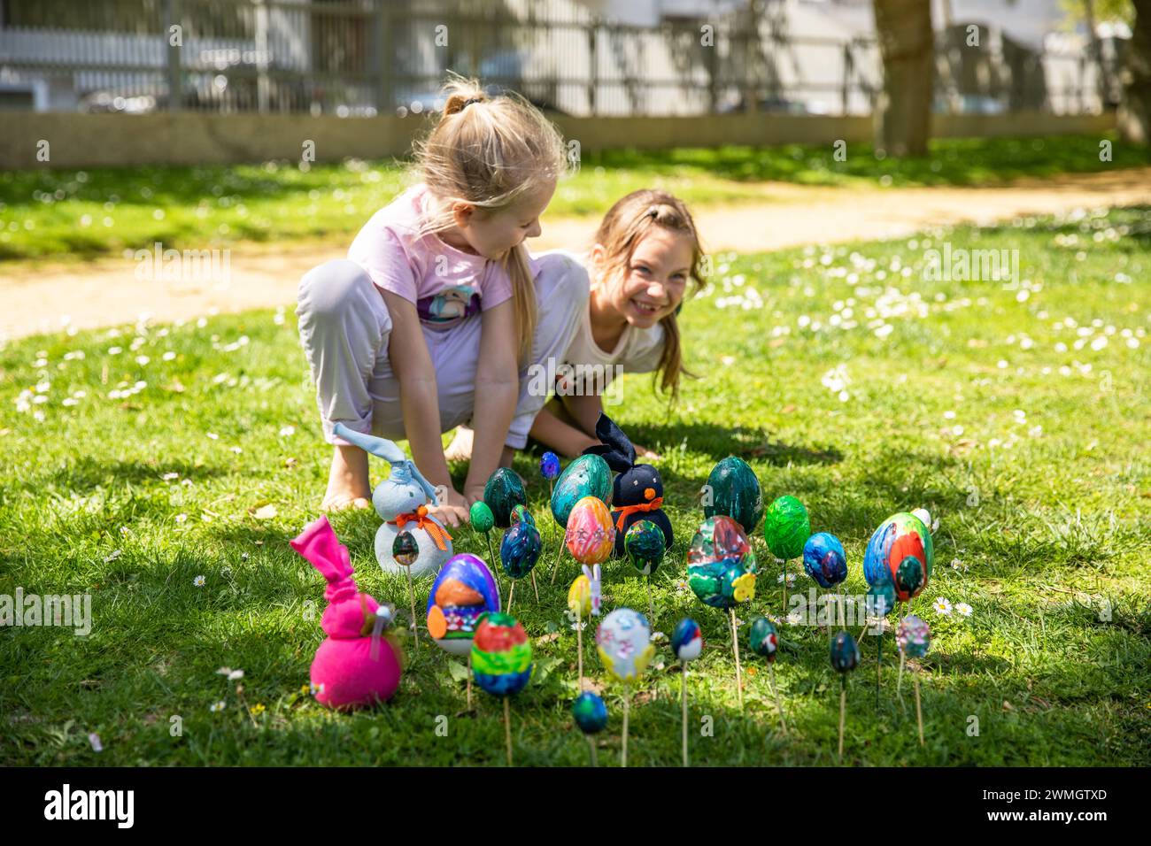 Zwei fröhlich schöne Mädchen spielen fröhlich im Park auf einem grünen Rasen an einem sonnigen Frühlingstag. Stockfoto