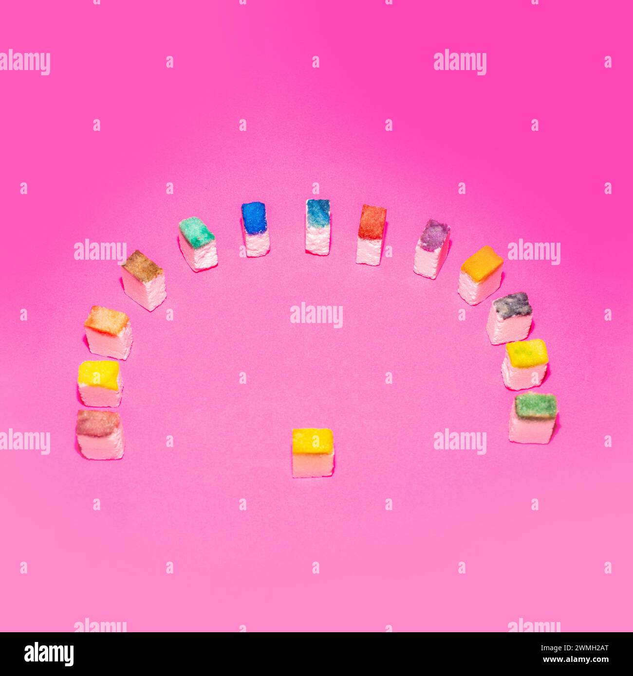 Bunte Zuckerwürfel in Form einer Menschenmenge auf rosa Hintergrund. Menschen-Metapher. Kreatives Lebensmittelkonzept. Stockfoto