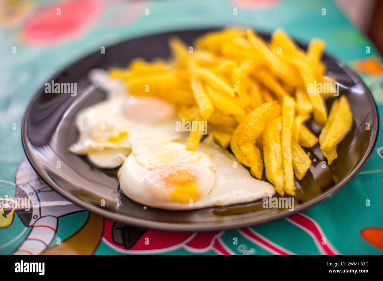 Ein Teller mit knusprigen Pommes frites, gepaart mit sonnigen Eiern aus Freilandhaltung. Stockfoto