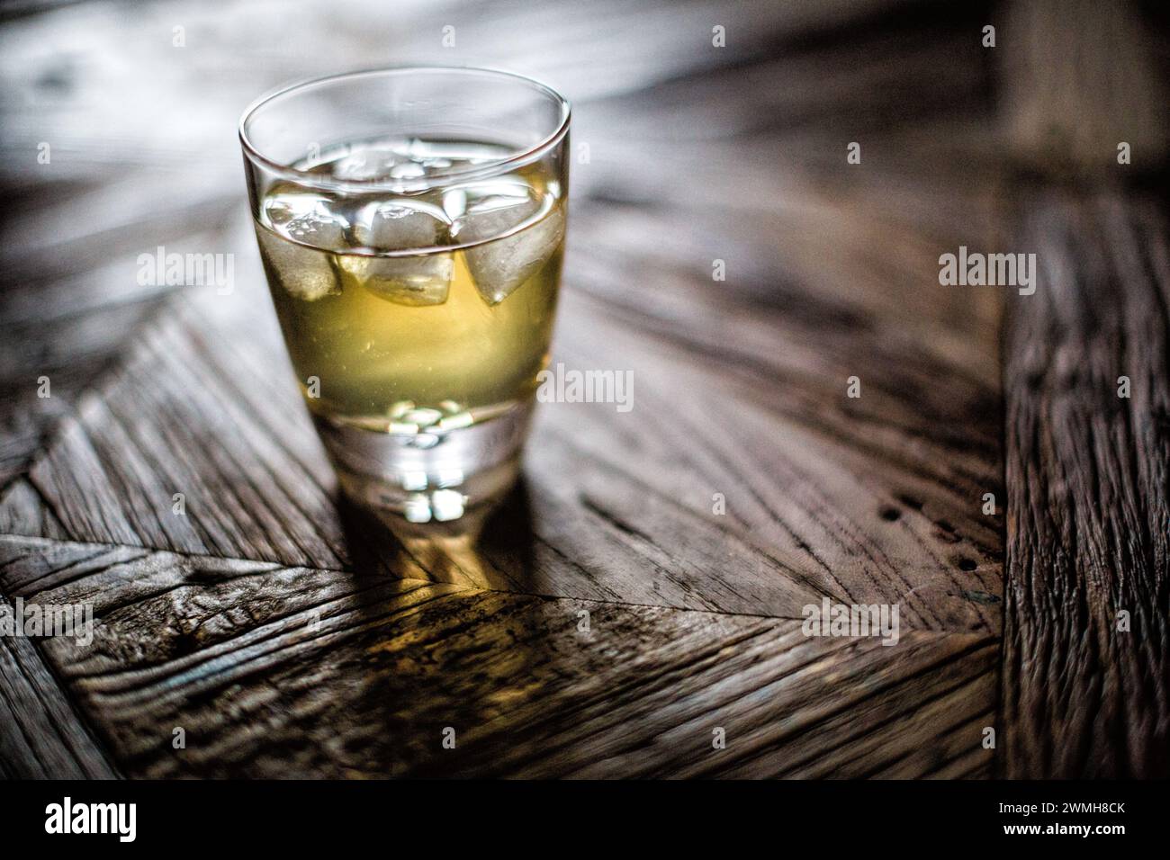 Ein Whiskey-Shot mit Eiswürfeln auf einer Holzoberfläche. Stockfoto