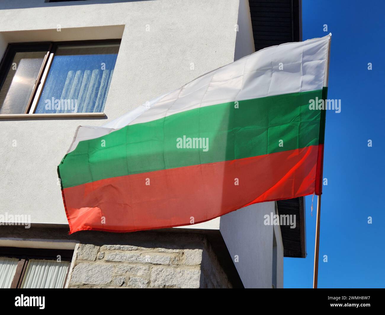 Die bulgarische Flagge flattert im Wind in der Nähe eines Gebäudes Stockfoto
