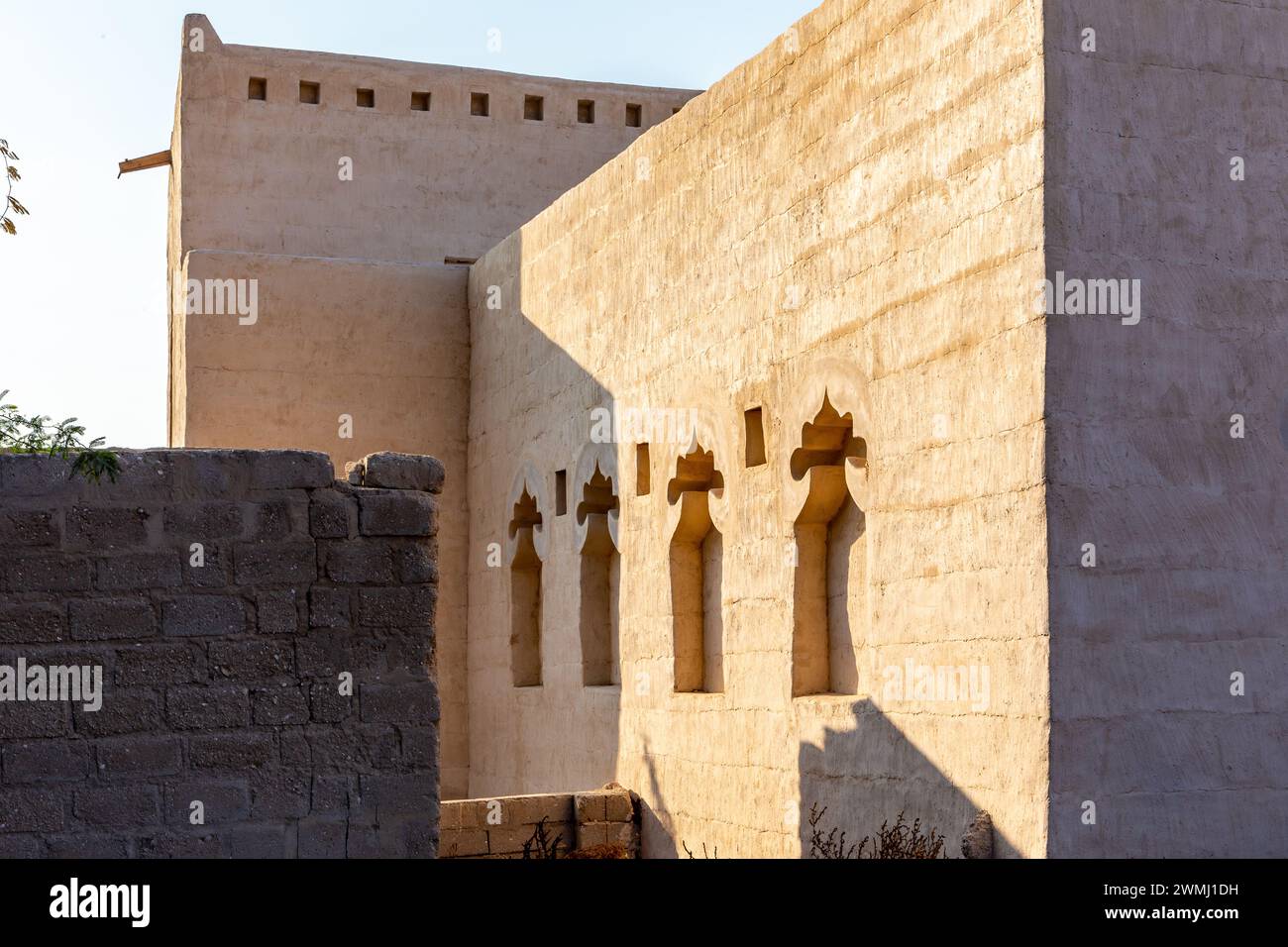 Alte Ziegelmauer im arabischen Stil mit traditionellen Nischen in Al Jazirah Al Hamra verlassene Stadt in den Vereinigten Arabischen Emiraten. Stockfoto