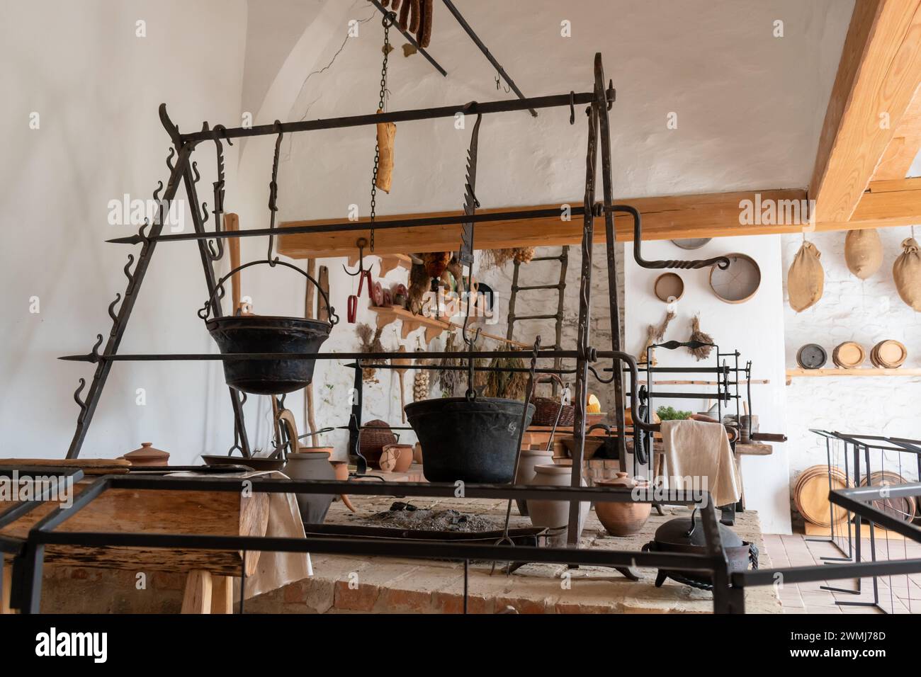 Alte Burgküche mit hängenden Kesseln und Kräutern. Stockfoto