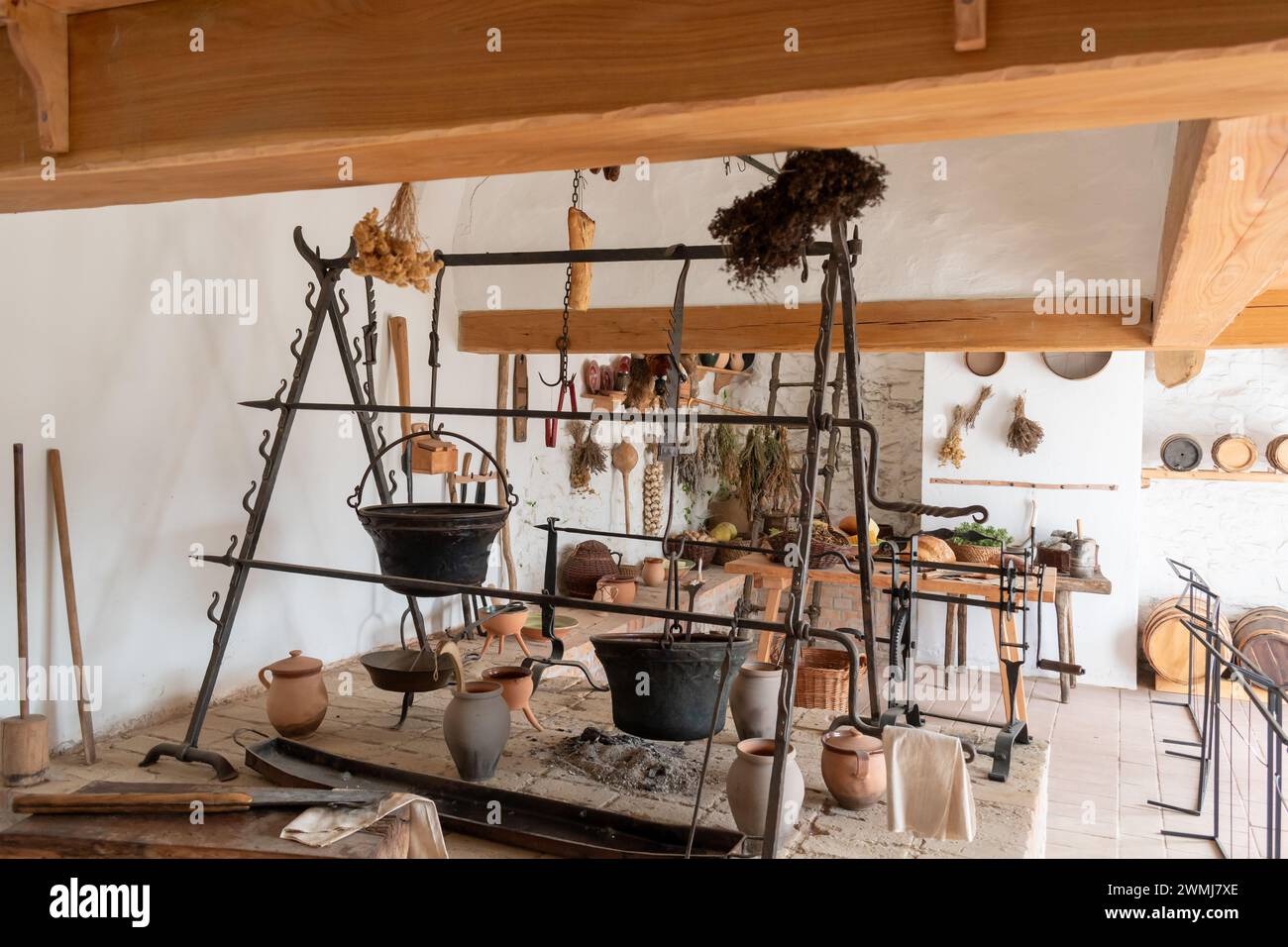 Alte Burgküche mit hängenden Kesseln und Kräutern. Stockfoto