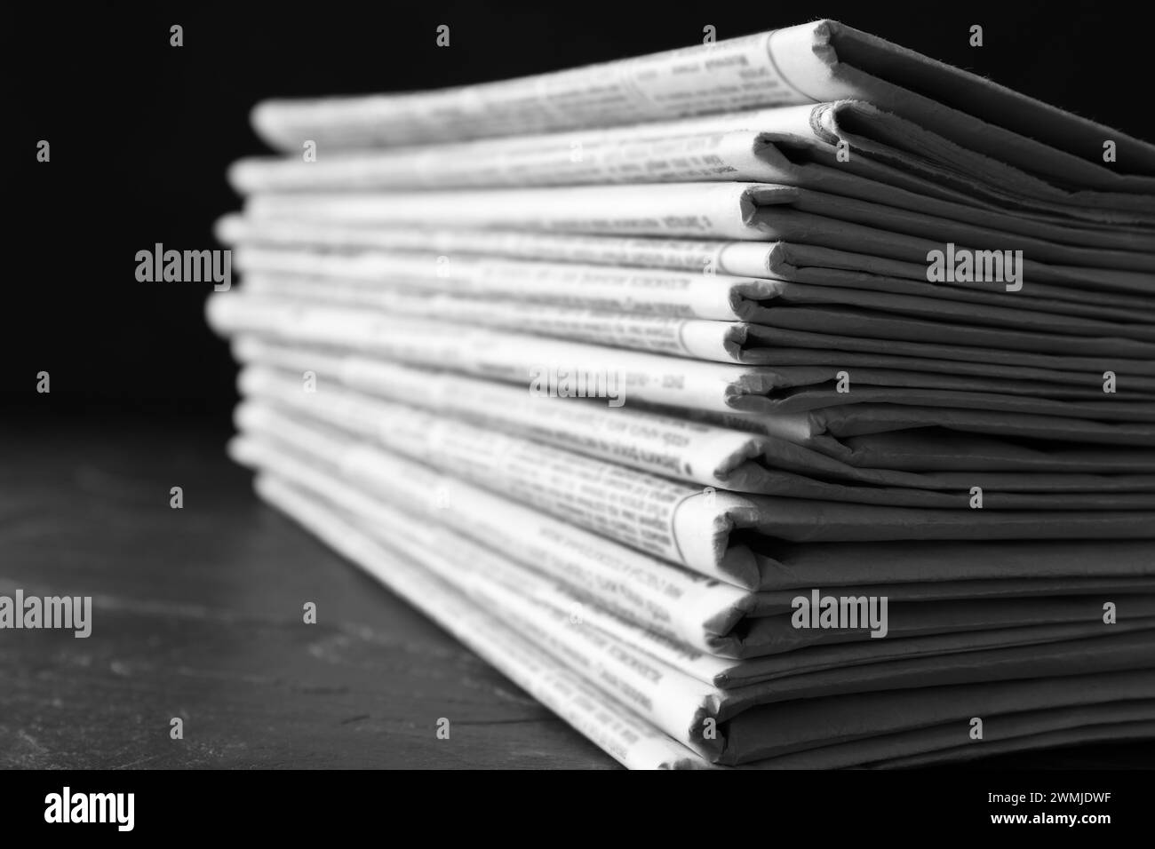 Stapel Zeitungen auf dunklem Steintisch, Nahaufnahme. Journalistenarbeit Stockfoto