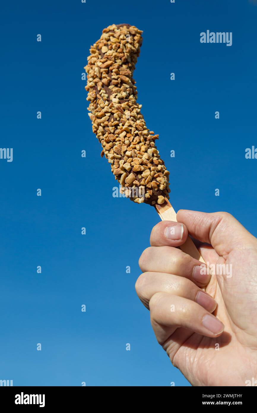 Eine mit Schokolade und Nüssen überzogene gefrorene Banane Stockfoto