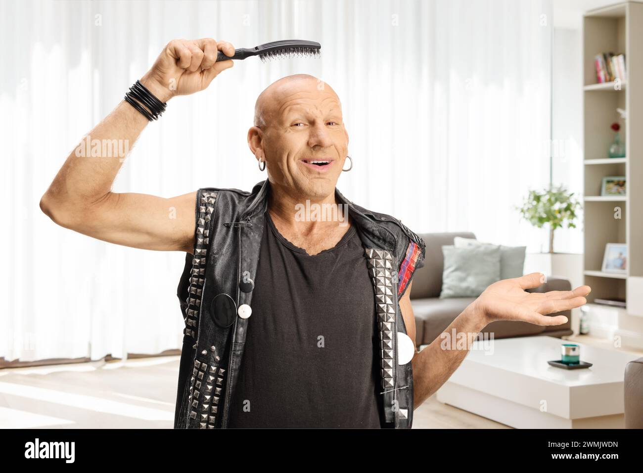 Ein lächelnder kahler Mann, der zu Hause eine Haarbürste über dem Kopf hält Stockfoto