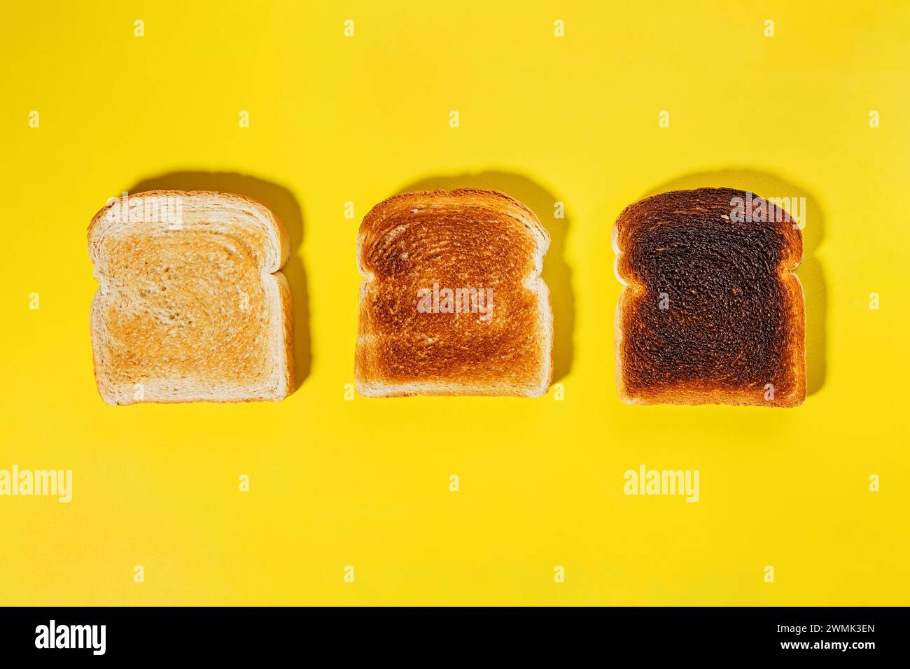 Verschiedene Toaststufen, geröstete quadratische Brotscheiben isoliert auf gelbem Hintergrund Stockfoto