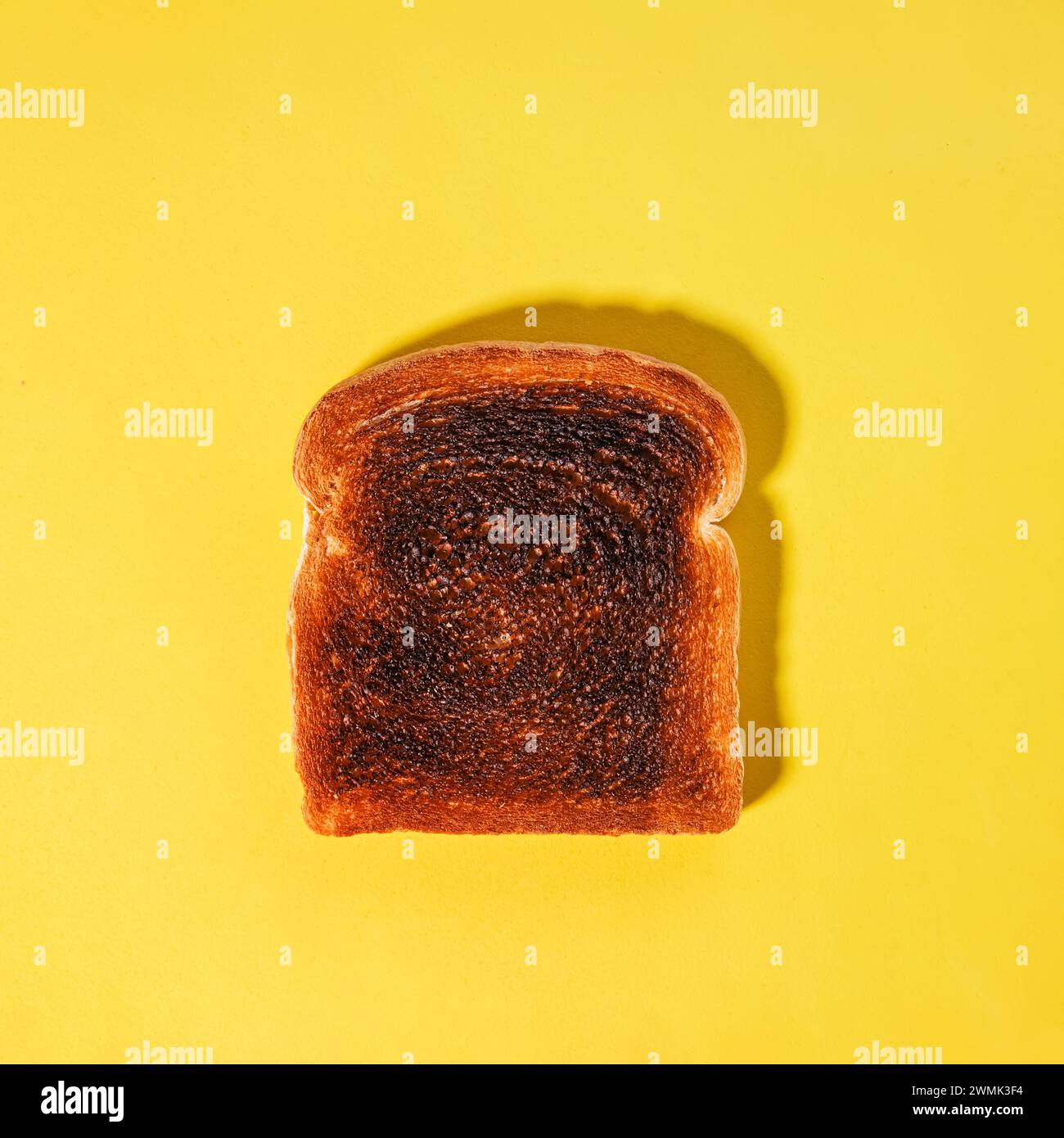 Quadratische Brotscheibe, verbrannter Toast isoliert auf gelbem Hintergrund Stockfoto