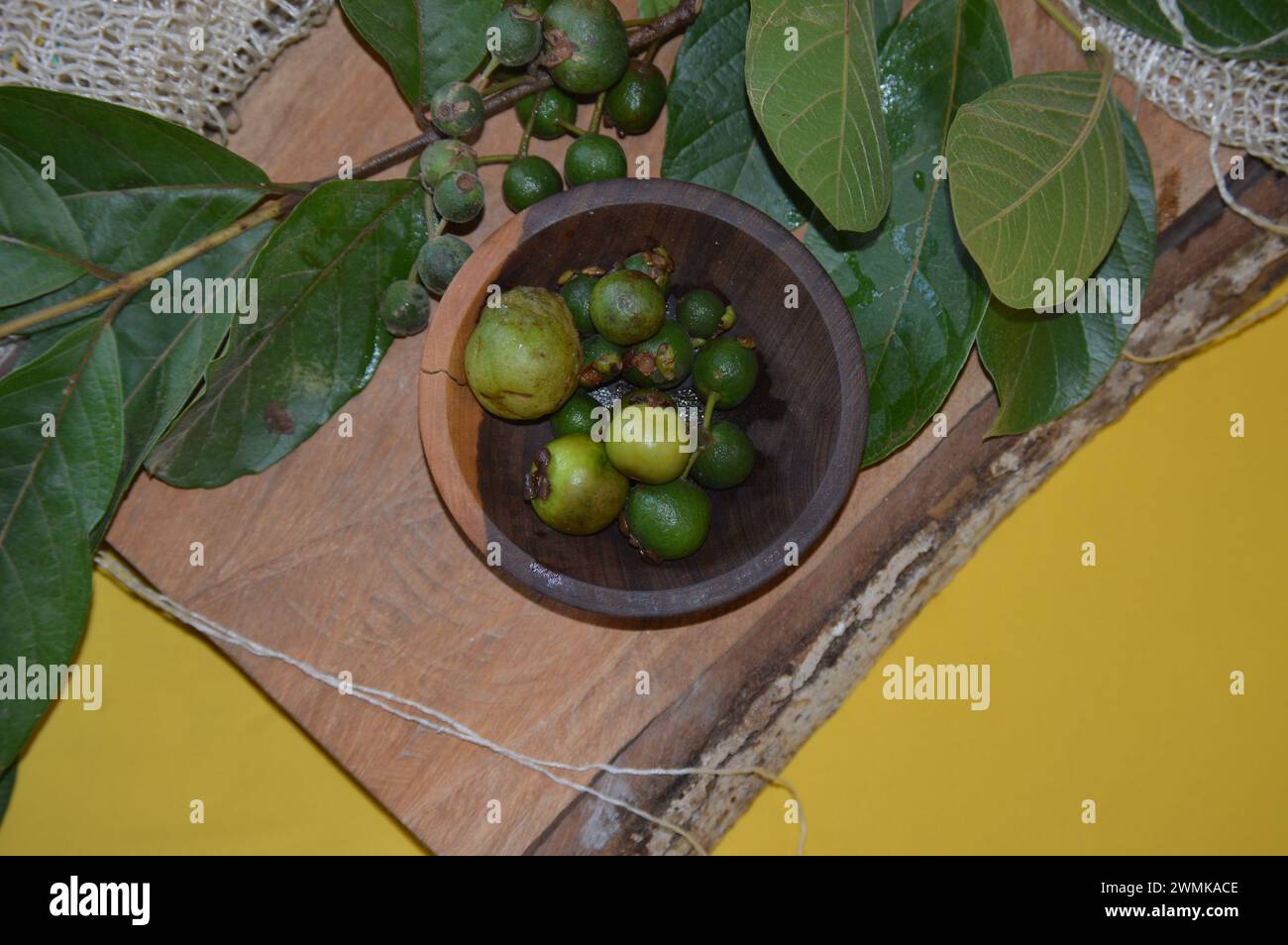 Araçá- oder Cattley-Guave-Frucht mit wissenschaftlichem Namen (Psidium Cattleianum) in rustikaler Holzschale Stockfoto