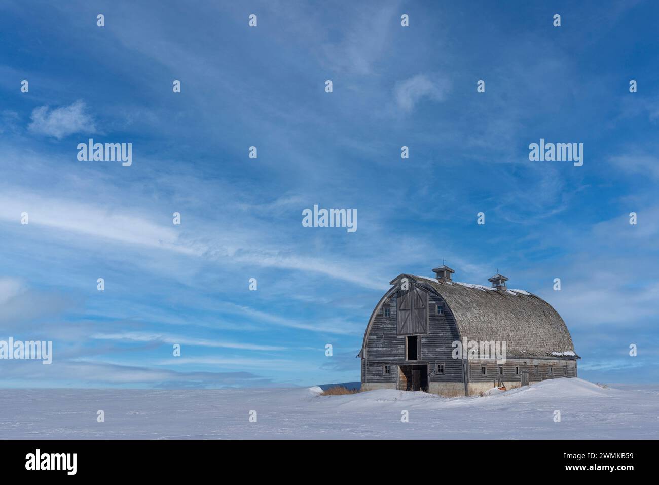 Verlassene Scheune im Winter irgendwo im ländlichen Saskatchewan. Der wunderschöne blaue Himmel schafft eine atemberaubende Komposition; Saskatchewan, Kanada Stockfoto