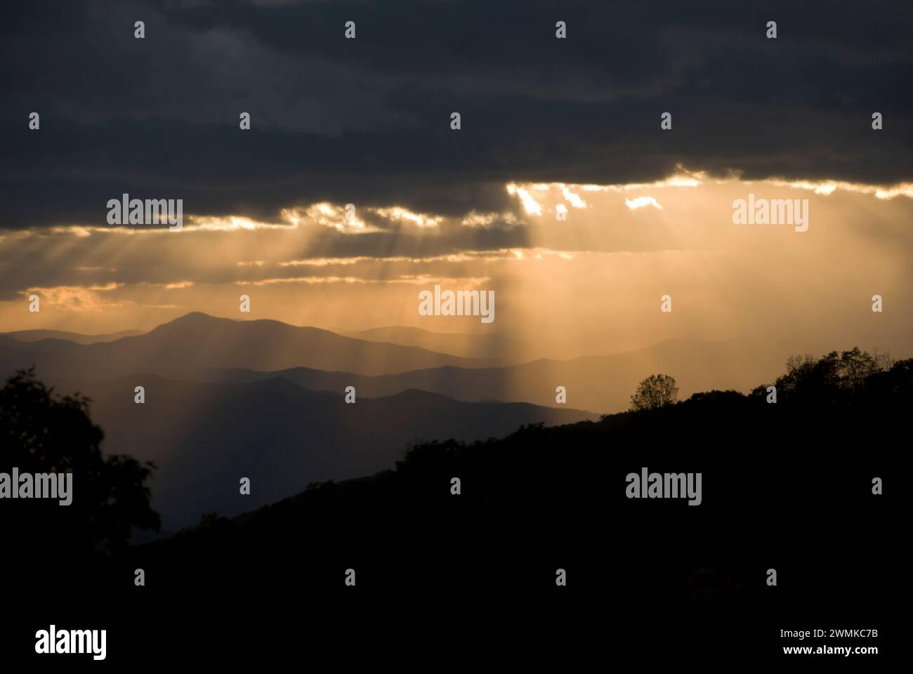 Sonnenlicht strömt durch die dunklen Wolken über die Blue Ridge Mountains bei Sonnenuntergang; North Carolina, Vereinigte Staaten von Amerika Stockfoto