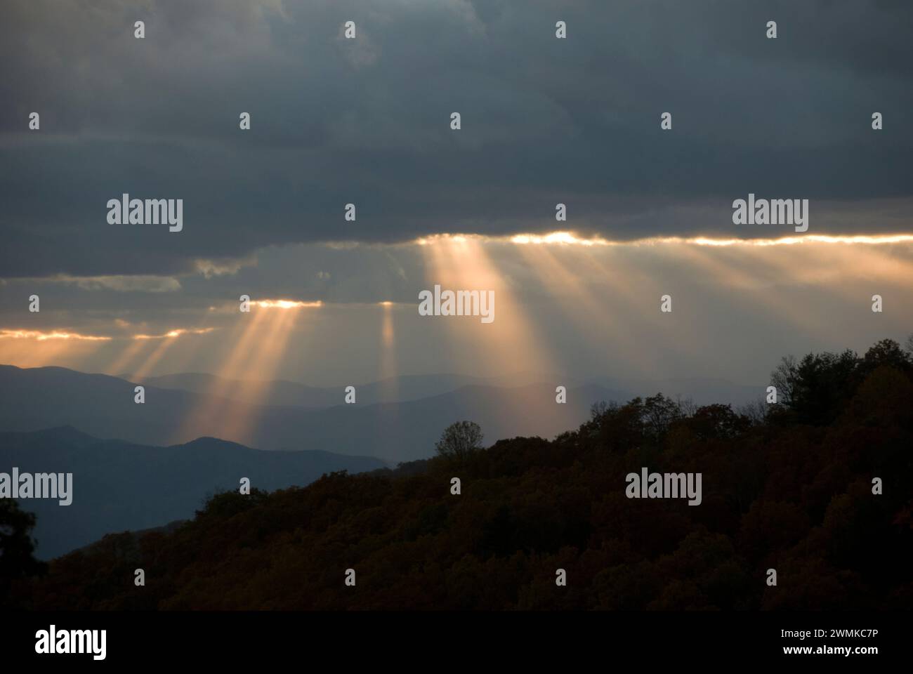 Sonnenlicht strömt durch die Brüche in den grauen Wolken über die Blue Ridge Mountains in der Dämmerung; North Carolina, Vereinigte Staaten von Amerika Stockfoto
