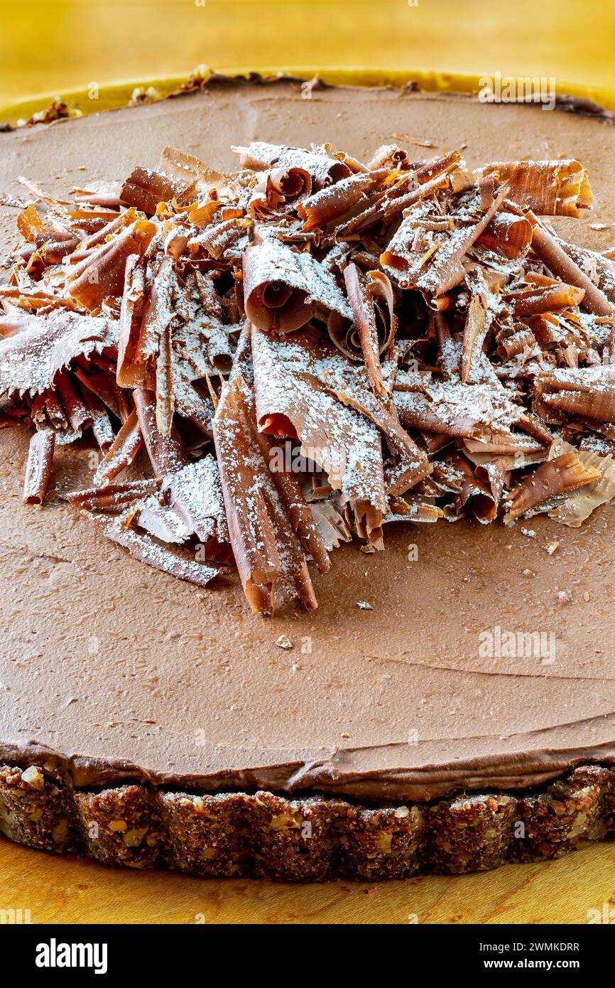 Nahaufnahme eines Schokoladen-Mousse-Pie mit Krustenboden auf einem hölzernen Schneidebrett und Glasur mit Schokolade darüber; Studio Stockfoto