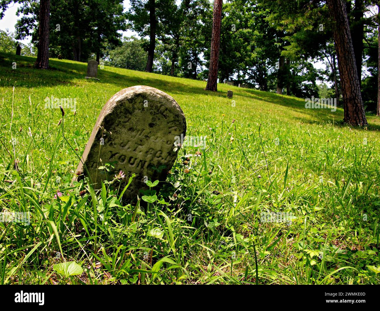 Alter Grabstein, der auf einem grasbewachsenen Hügel liegt Stockfoto