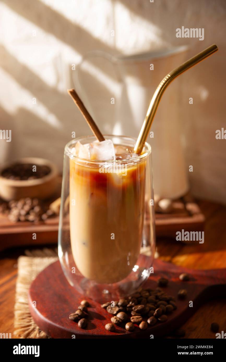 Eiskaffee serviert in einer doppelwandigen Glasschale und Metallstroh, ein kaltes Sommergetränk mit Eiswürfeln und Gewürzen, Zimt, Muskatnuss, Vanille, Mu Stockfoto