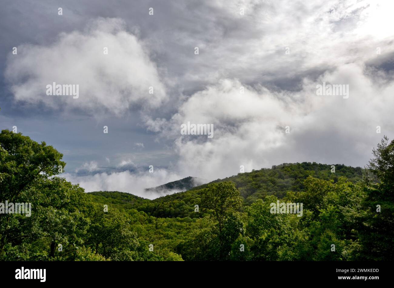 Sturmwolken ziehen sich über Berge mit üppiger grüner Vegetation Stockfoto