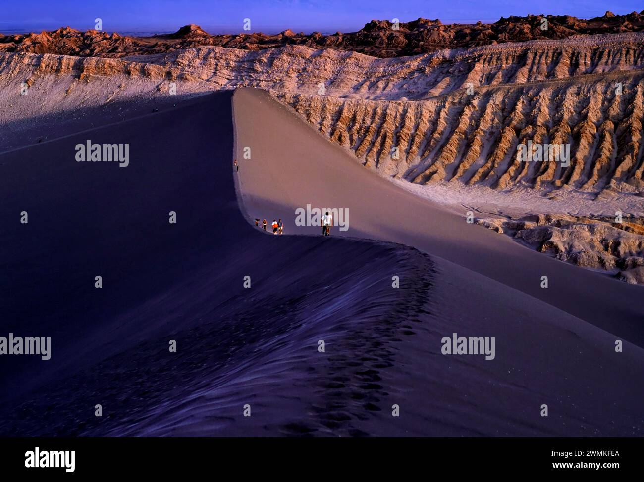 Wanderer, die auf dem Gipfel einer großen Düne in der Atacama-Wüste spazieren, einer Region im Norden Chiles, die als der trockenste Ort der Erde gilt. Loca... Stockfoto