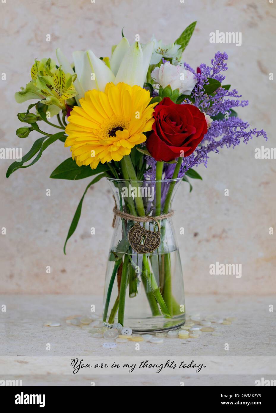 Kleiner, farbenfroher Blumenstrauß in einer Glasvase mit einer durchdachten Botschaft im Text und einem herzförmigen, dekorativen Charme, der um den Hals gebunden ist; Studio Shot Stockfoto