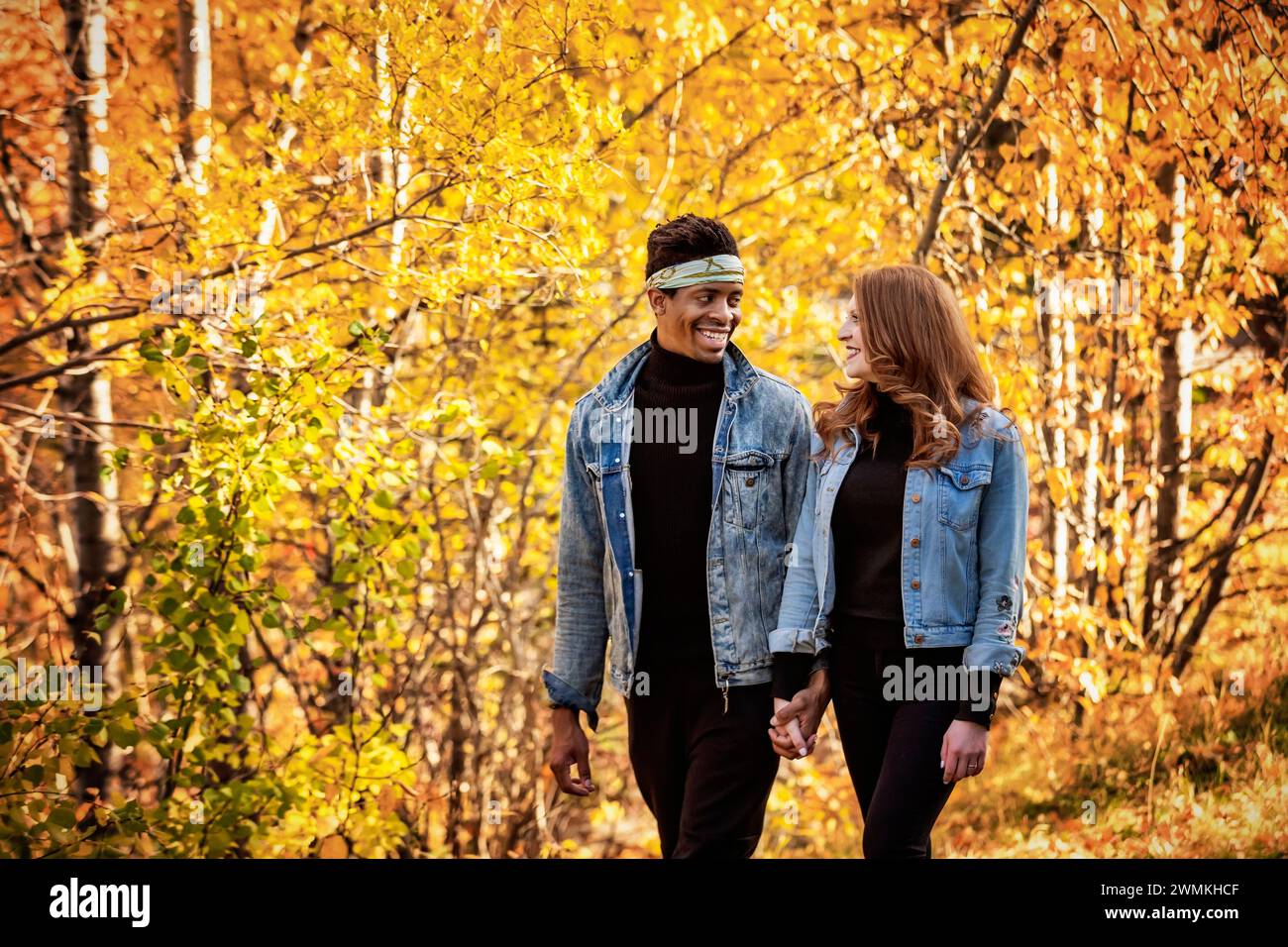 Nahaufnahme einer gemischten Rasse verheiratete Paare, die sich gegenseitig anlächeln, während eines Familienausflugs im Herbst durch einen Stadtpark spazieren gehen und gute Zeit miteinander verbringen Stockfoto