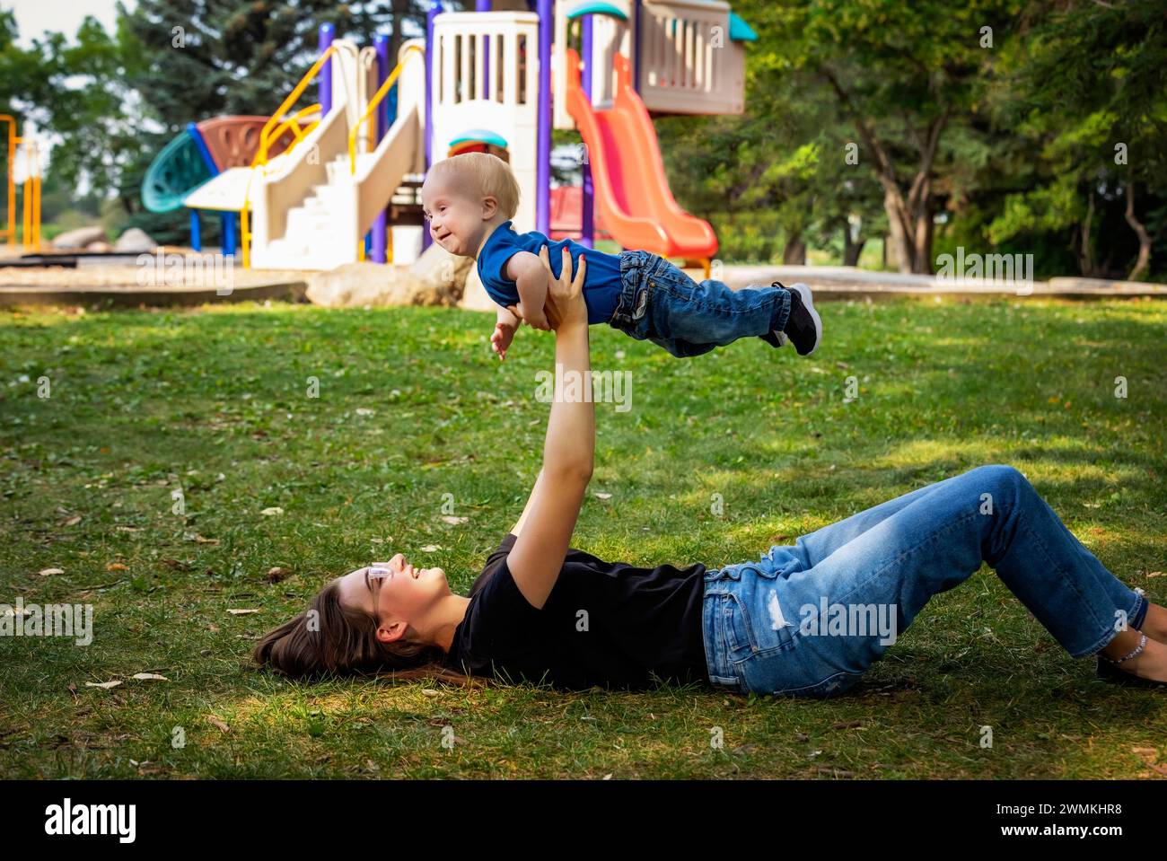 Schwester verbringt schöne Zeit im Freien mit ihrem kleinen Bruder, der das Down-Syndrom hat, in einem Stadtpark an einem warmen Herbstnachmittag Stockfoto