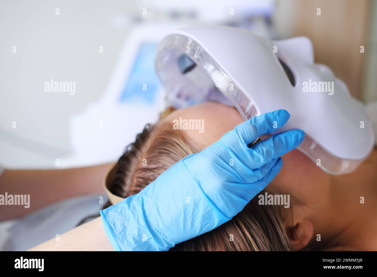 Nahaufnahme eines Patienten, der in einer Schönheitsklinik eine hochmoderne LED-Gesichtsmaskenbehandlung erhält. Horizontales Foto Stockfoto