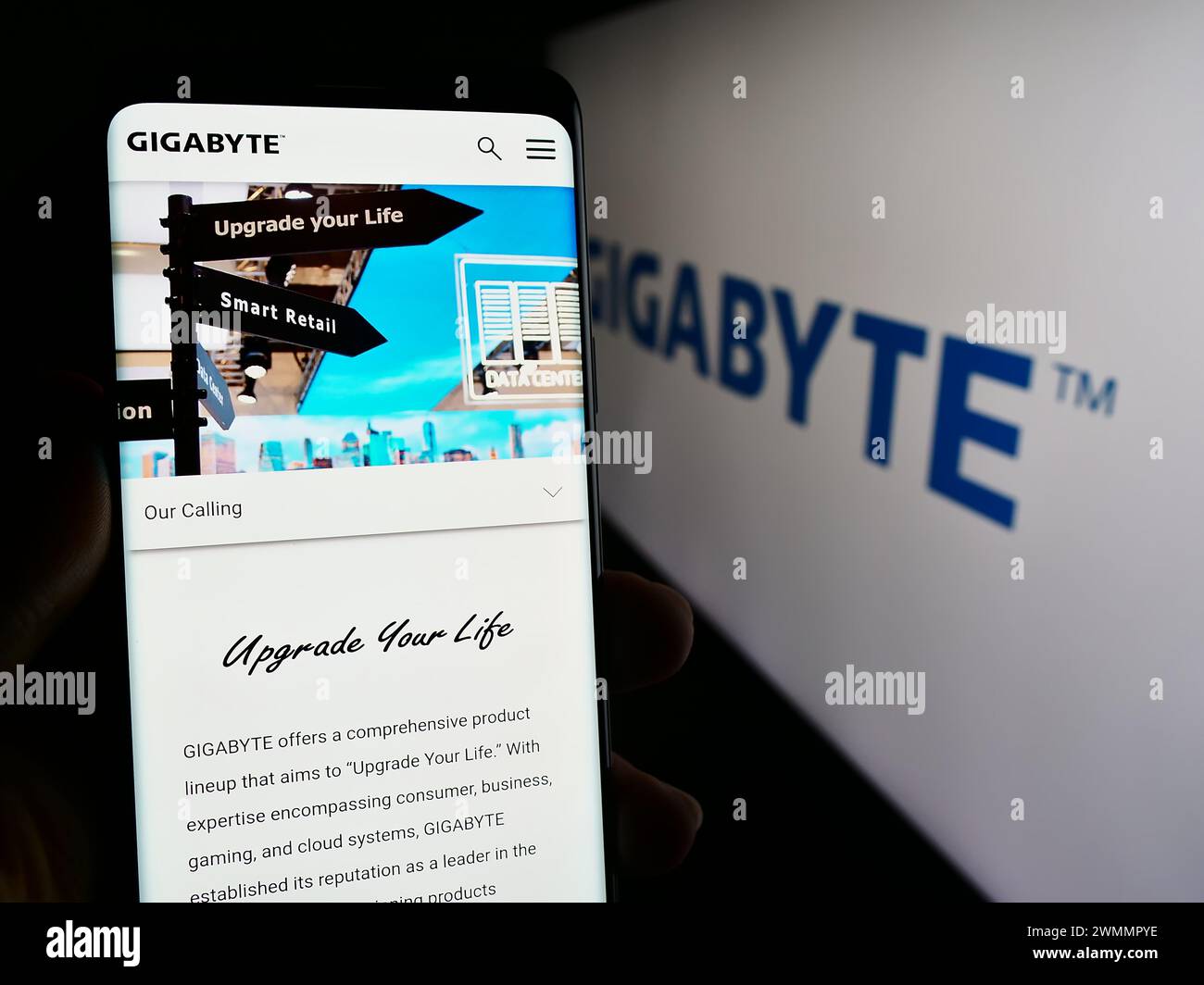 Person mit Smartphone und Webseite des taiwanesischen Computerhardware-Unternehmens Gigabyte Technology mit Logo. Konzentrieren Sie sich auf die Mitte des Telefondisplays. Stockfoto