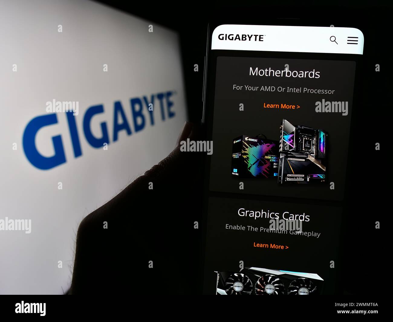Person, die ein Mobiltelefon mit Webseite des taiwanesischen Computerhardware-Unternehmens Gigabyte Technology mit Logo hält. Konzentrieren Sie sich auf die Mitte des Telefondisplays. Stockfoto