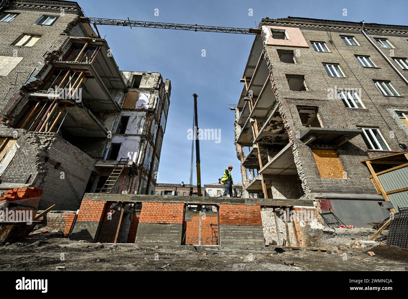 Nicht exklusiv: ZAPORIZHZHIA, UKRAINE - 26. FEBRUAR 2024 - Bauarbeiter legen Ziegelsteine am Sockel und an den Wänden des Erdgeschosses der beschädigten Sekte Stockfoto