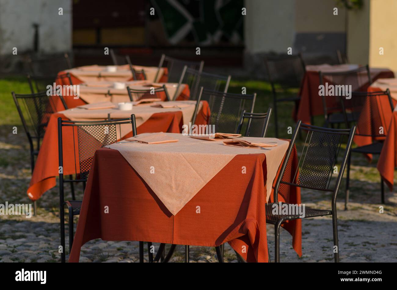 Tische eines Open-Air-Restaurants auf dem Platz eines touristischen Ortes, ein Tisch gut mit farbigen Tischdecken vorbereitet, an Feiertagen und Feiertagen die meisten Touristen Stockfoto