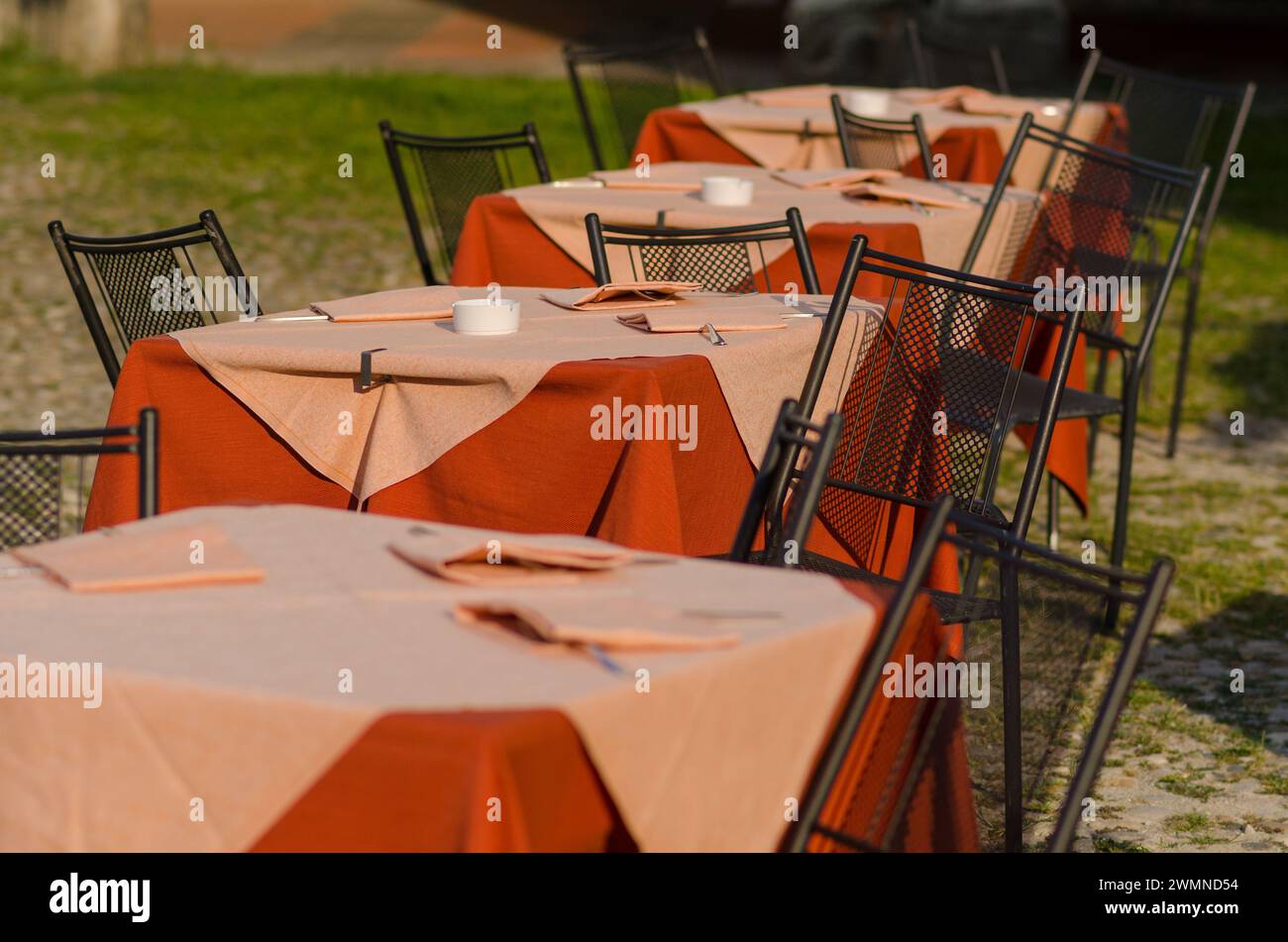 Tische eines Open-Air-Restaurants auf dem Platz eines touristischen Ortes, ein Tisch gut mit farbigen Tischdecken vorbereitet, an Feiertagen und Feiertagen die meisten Touristen Stockfoto