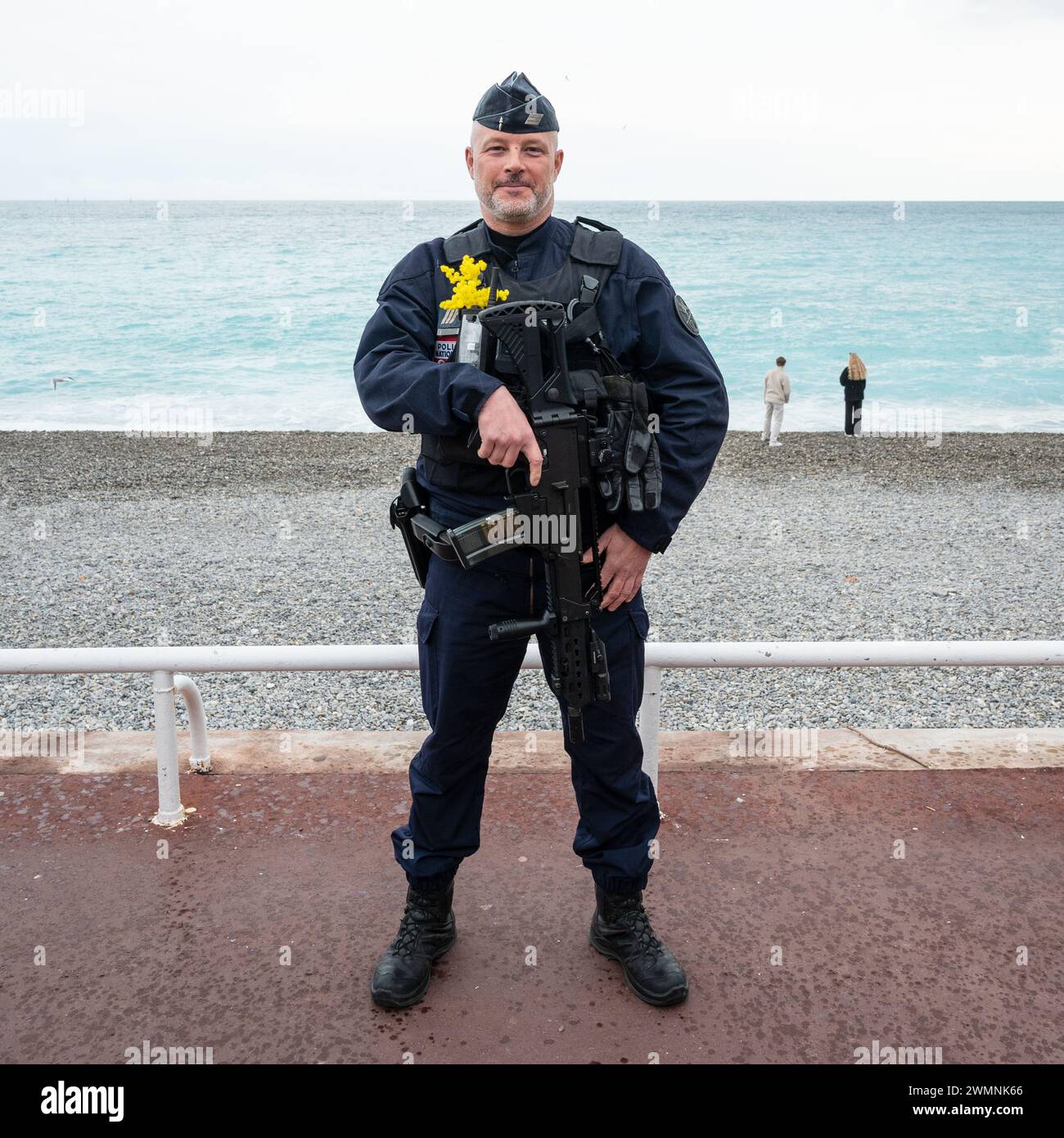 Bewaffneter Polizist mit Blumen am Strand beim Karneval von Nizza, 24. Februar 2024 2023, war der 150. Jahrestag des Festivals von Nizza Stockfoto