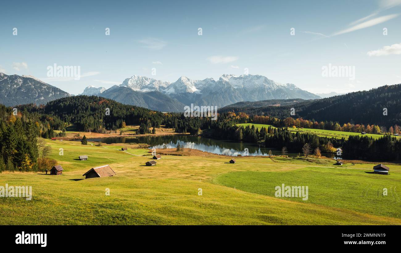 Geroldsee im Alpental bei Gerold Stadt an einem sonnigen Herbsttag: Kleine Holzscheune auf grüner Wiese und dahinter verschneite Karwendelgebirge. Stockfoto