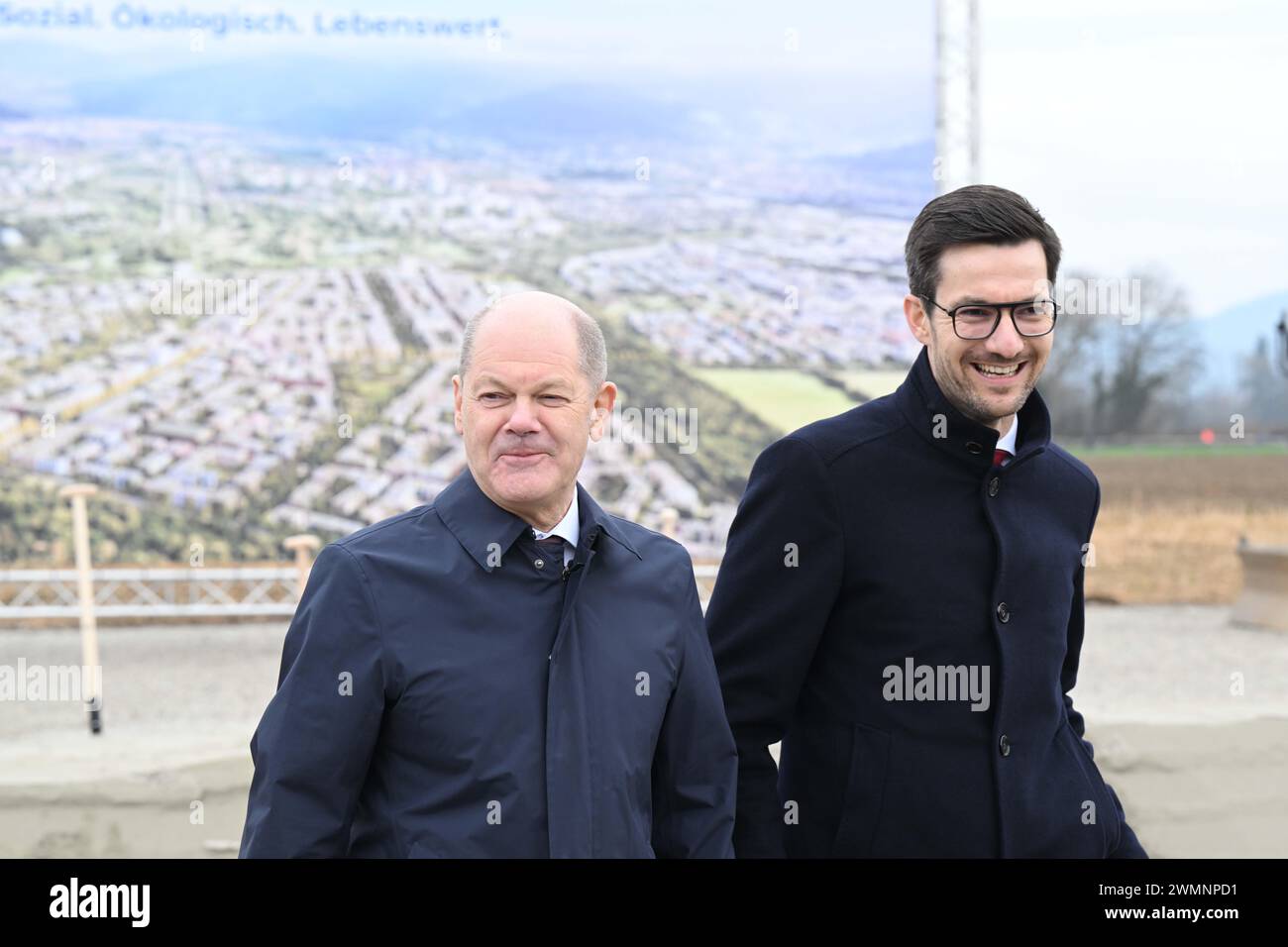 Freiburg, Deutschland. Februar 2024. Bundeskanzler Olaf Scholz (l, SPD) und Martin Horn, Oberbürgermeister der Stadt Freiburg, stehen bei einem Spatenstich für den großen neuen Stadtteil Dietenbach in Freiburg vor einem Banner mit einem Computerbild des Bauprojekts. Quelle: Bernd Weißbrod/dpa/Alamy Live News Stockfoto