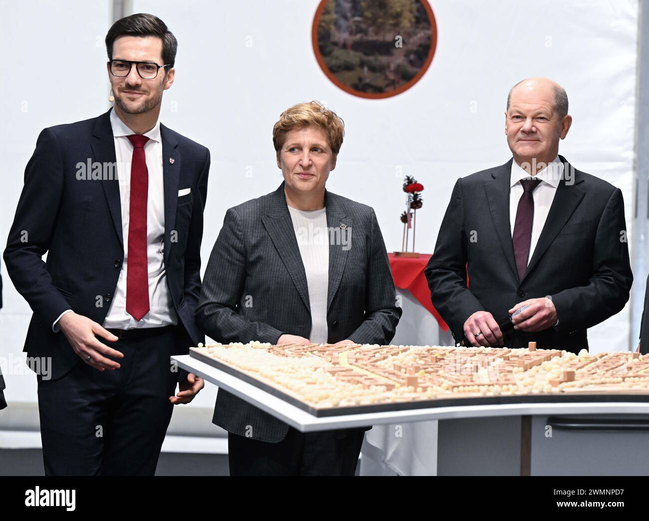 Freiburg, Deutschland. Februar 2024. Martin Horn (l-r), Oberbürgermeister der Stadt Freiburg, Nicole Razavi (CDU), baden-württembergische Ministerin für Wohnen und Regionalentwicklung, und Bundeskanzler Olaf Scholz (SPD) stehen bei einem Spatenstich für den großen neuen Stadtteil Dietenbach in Freiburg vor einem Modell des Bauprojekts. Quelle: Bernd Weißbrod/dpa/Alamy Live News Stockfoto