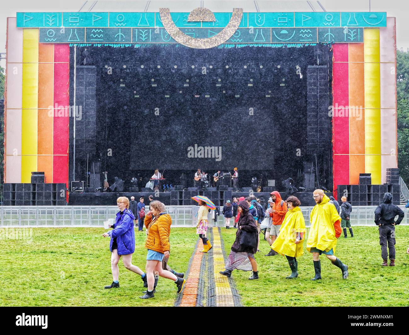 Crickhowell, Brecon Beacons, Wales, Großbritannien. August 2023. Das Green man Festival ist ein unabhängiges Musik-, Wissenschafts- und Kunstfestival, das jährlich Mitte August in den Brecon Beacons in Wales stattfindet. Green man hat sich zu einer Veranstaltung mit 25.000 Teilnehmern entwickelt, bei der überwiegend Live-Musik präsentiert wird. Im Bild: Festivalbesucher mit Regenschirm bei starkem Regen auf der fast verlassenen Hauptbühne Credit: Nidpor/Alamy Live News Stockfoto