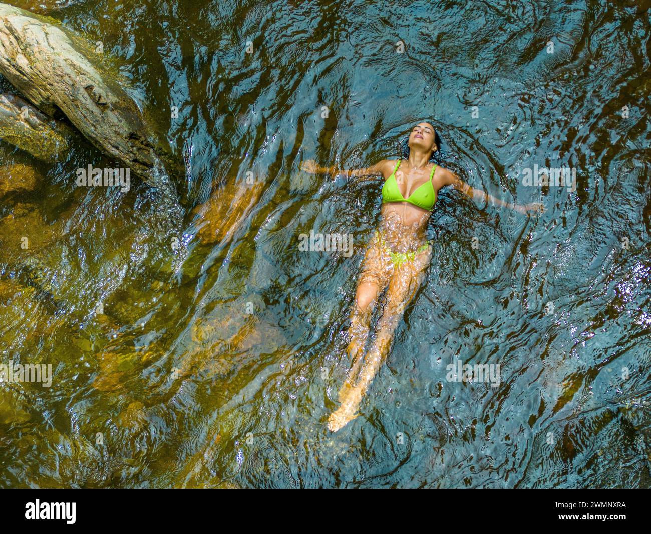 Drohnenfotografie mit erhöhter Aussicht einer weiblichen Touristen, die zu ostern im Wasser der Kaaterskill Falls schwimmt, einem zweistufigen Wasserfall am Spruce Creek Stockfoto