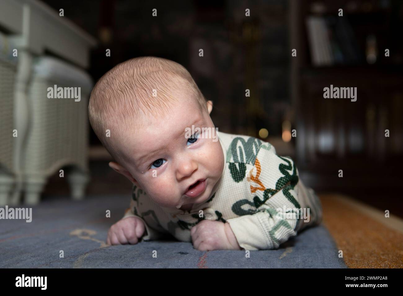 Zweieinhalb Monate alter Junge, der die Bauchzeit auf dem Boden genießt. Stockfoto
