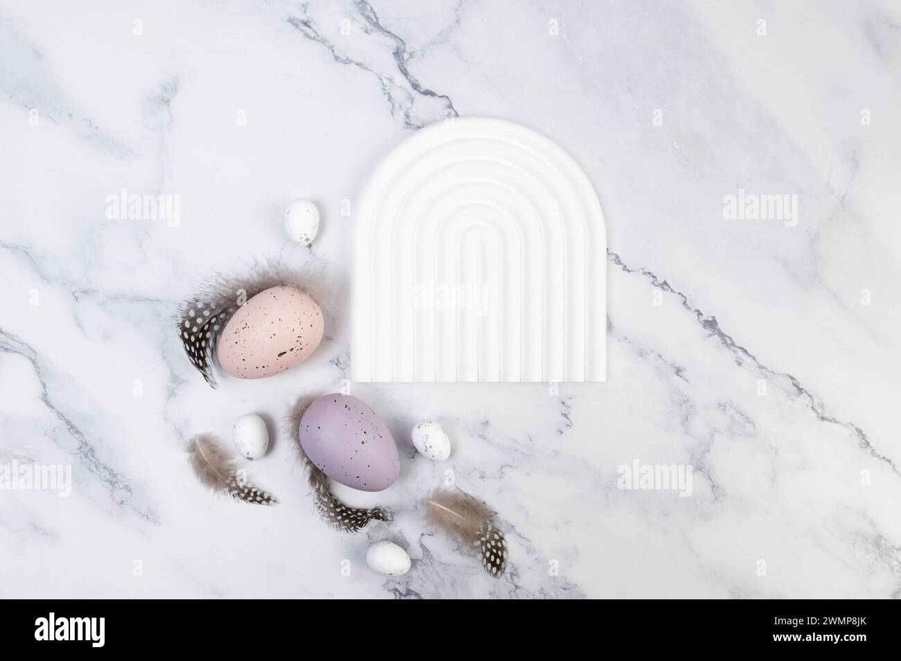 Blick von oben auf farbenfrohe ostereier auf weißem Marmorhintergrund. Weiße Bogenschale, Produktpräsentation. Kreative osterkomposition, Frühling, Kopierraum. Stockfoto