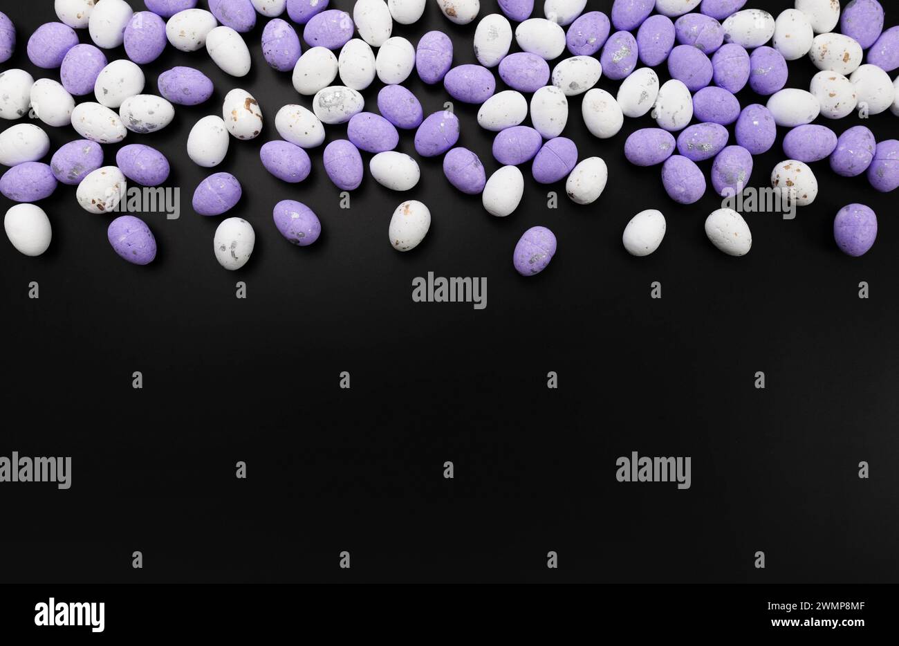 Blick von oben auf violette und weiße ostereier auf schwarzem Hintergrund. Kreative osterkomposition, Frühling, Kopierraum, flache Lay. Stockfoto