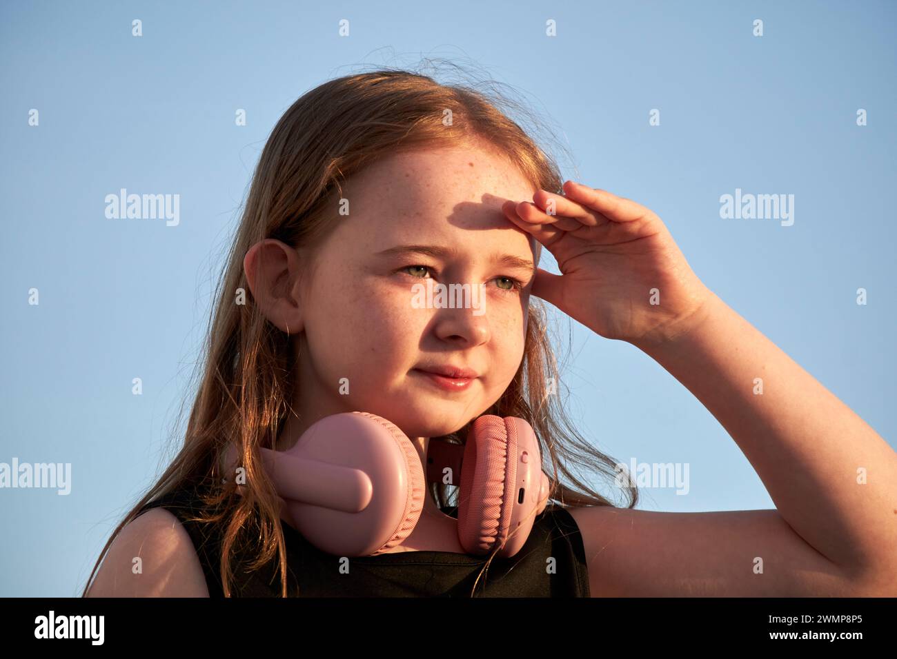 Junges 10-jähriges Mädchen, das die Augen schattiert und den Sonnenuntergang auf Lanzarote, Kanarischen Inseln, spanien betrachtet Stockfoto