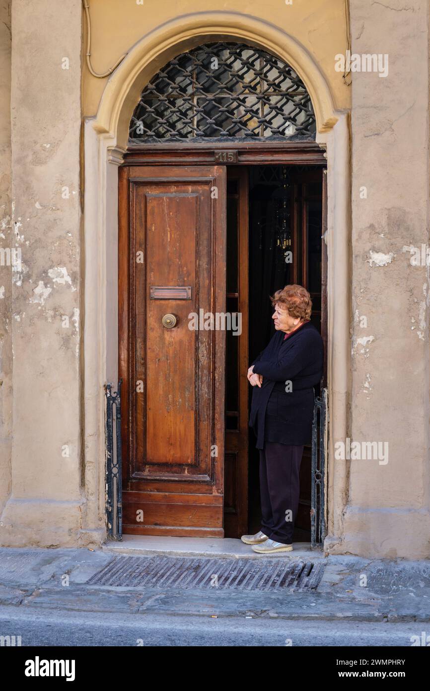 Eine Frau, die aus ihrer Tür schaut, Senglea, Valletta, Malta Stockfoto