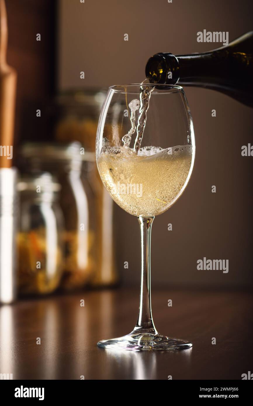 Freeze Motion in französischem Weißwein in ein Glas in Blasen mit einem Spritzer auf dem Tisch in der Küche, ein hochwertiges Studio-Shooting aus nächster Nähe Stockfoto